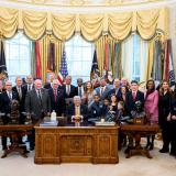 Members of Congress gather with the President before the bill is signed into law