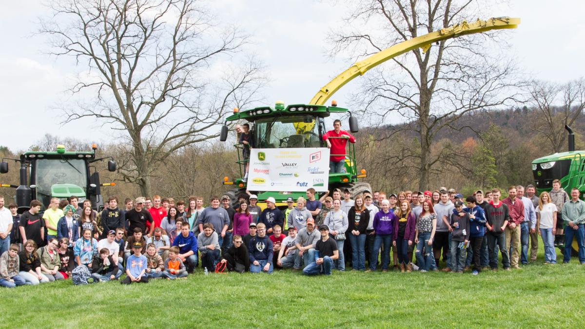 People standing in front of three tractors